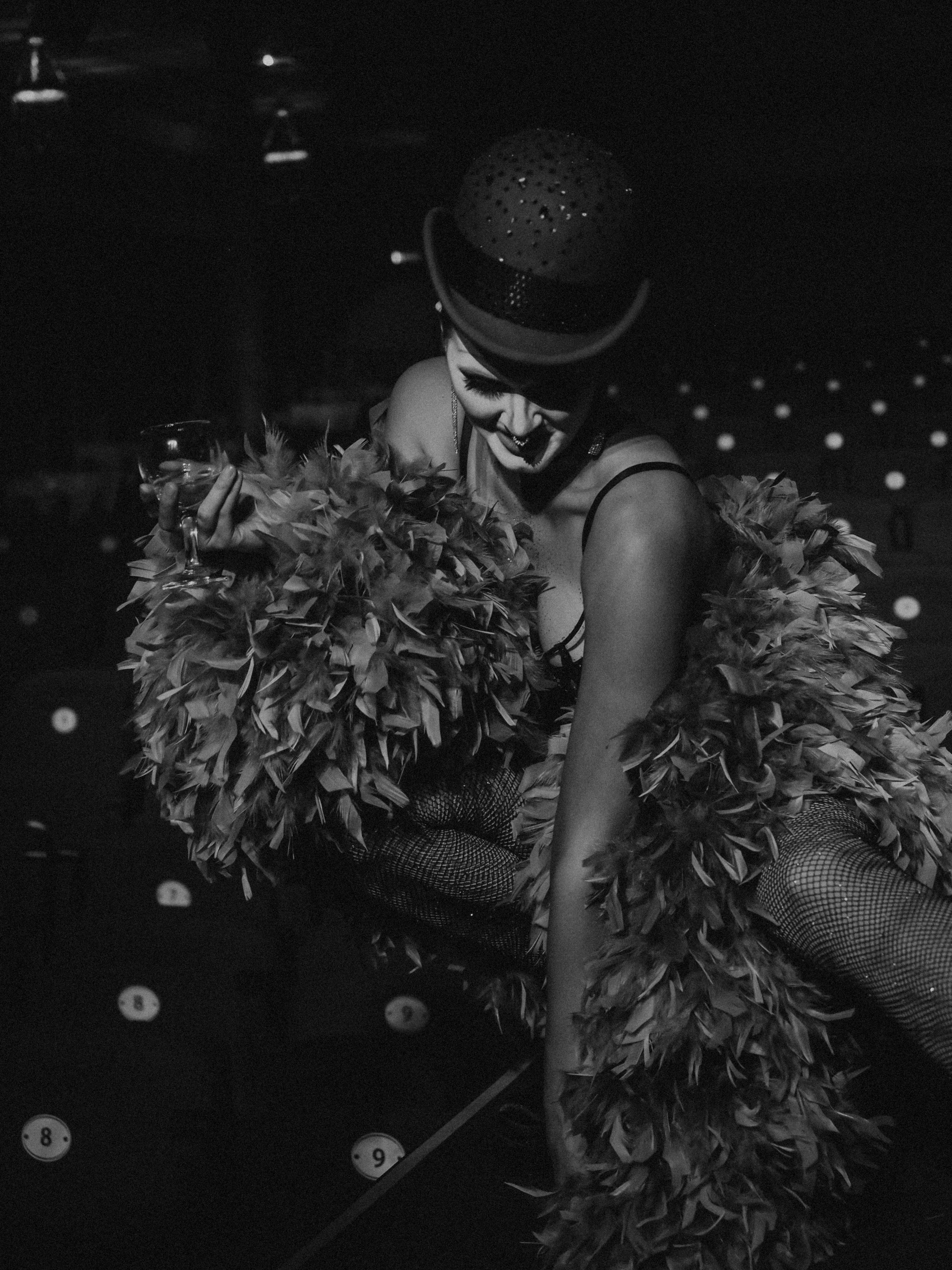 Courtesans Who Became Cultural Icons: The Real Reason History Still Remembers Them 2 Black and white cabaret performer in feathers holding a drink on stage